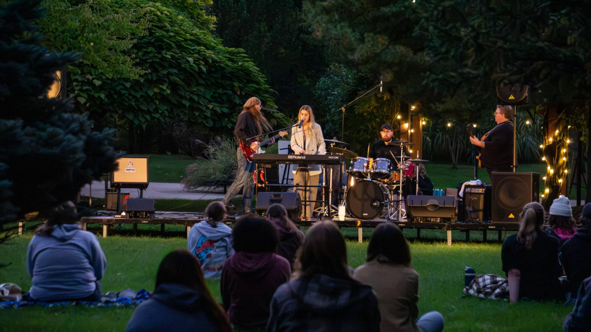 Four people standing on a stage outside
